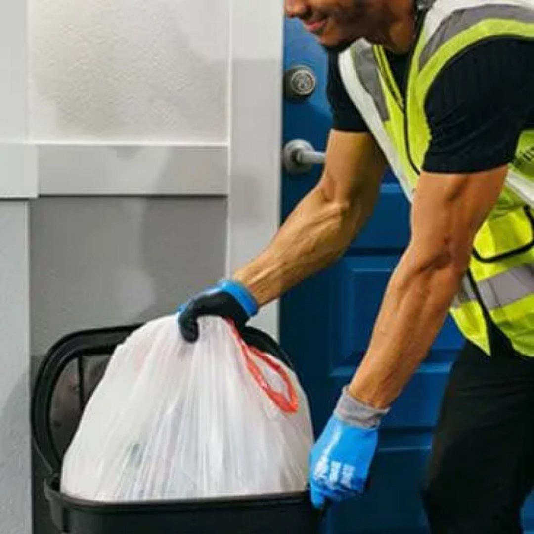 Valet trash team member collecting a bag at an apartment door.